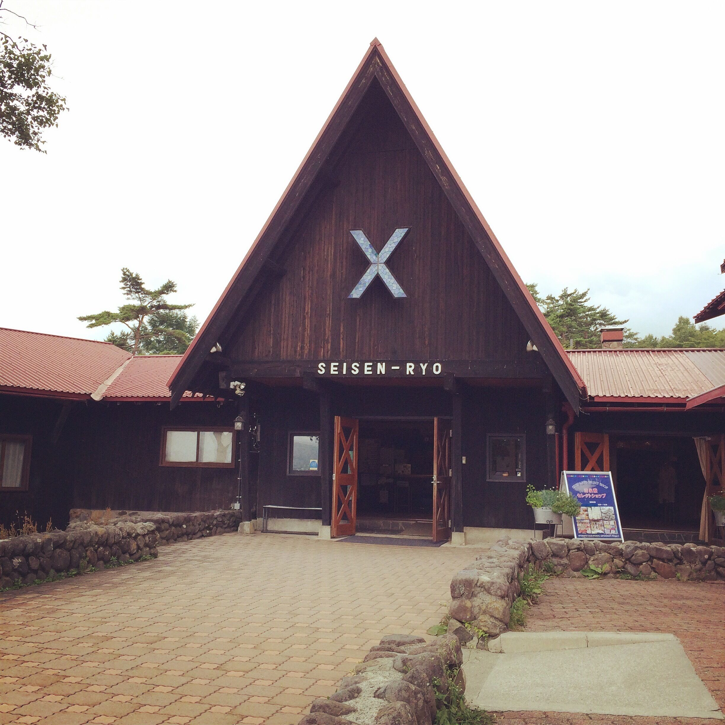 A wooden building with a triangular roof and a large 'X' on the front.