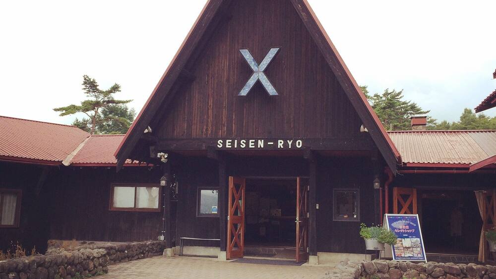 A wooden building with a triangular roof and a large 'X' on the front.