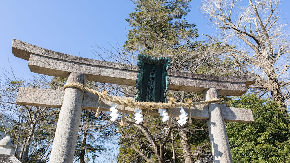 Ein traditionelles japanisches Torii-Tor mit Seilen und weißen Papierdekorationen.