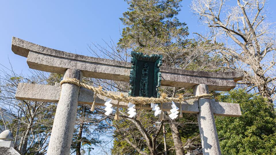 A traditional Japanese torii gate with ropes and white paper decorations.