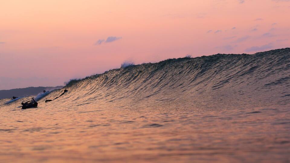 A large wave with surfers riding it.