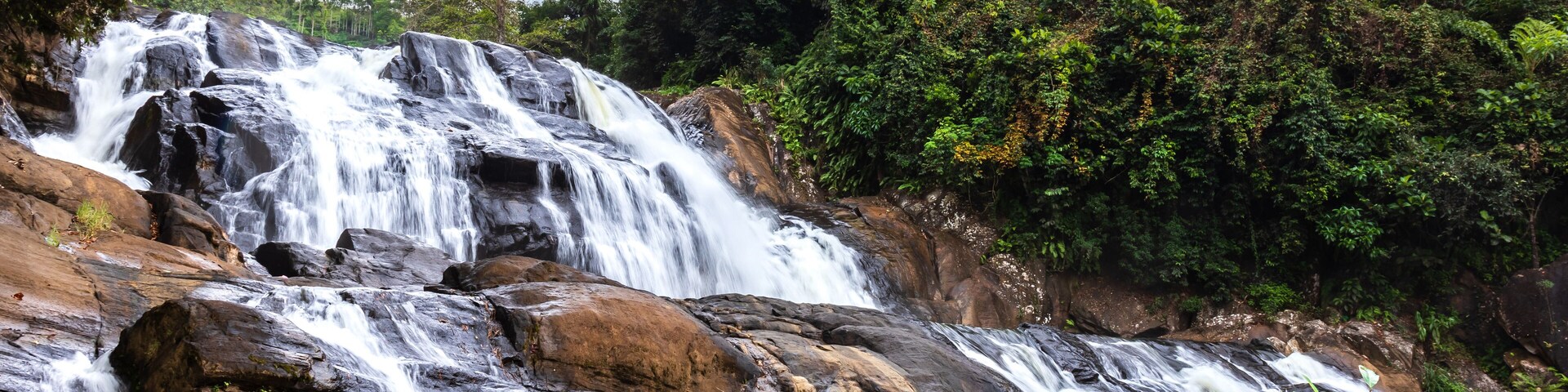 Uma cascata em vários níveis, cercada por uma floresta densa.