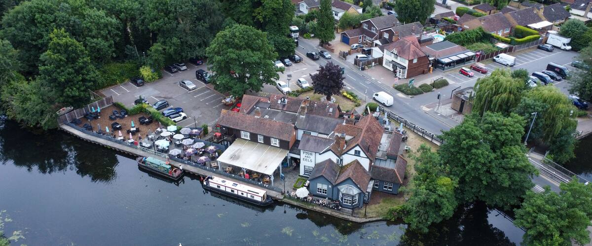 A riverside town with a pub, boats, and residential houses.