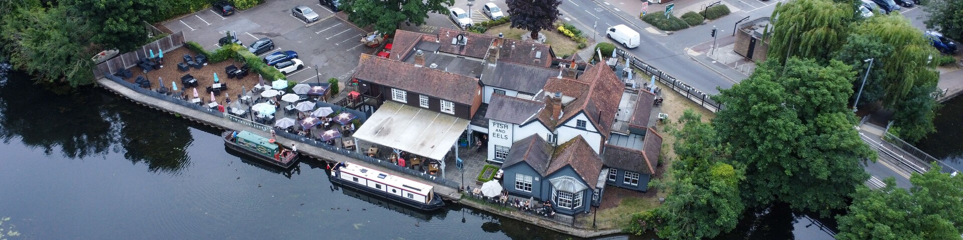A riverside town with a pub, boats, and residential houses.