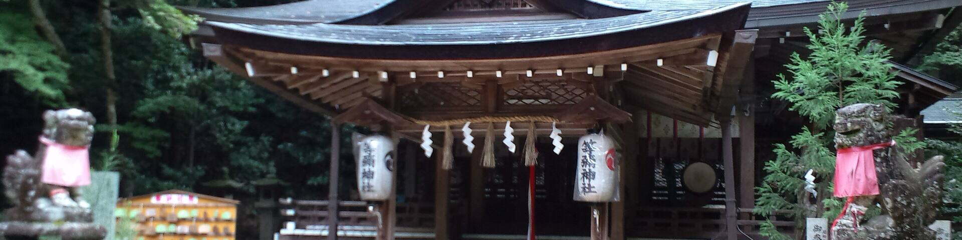 A traditional Japanese temple with a curved roof, surrounded by lush greenery.