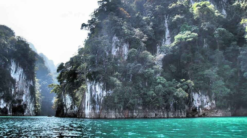A coastal landscape with towering limestone cliffs and clear turquoise waters.