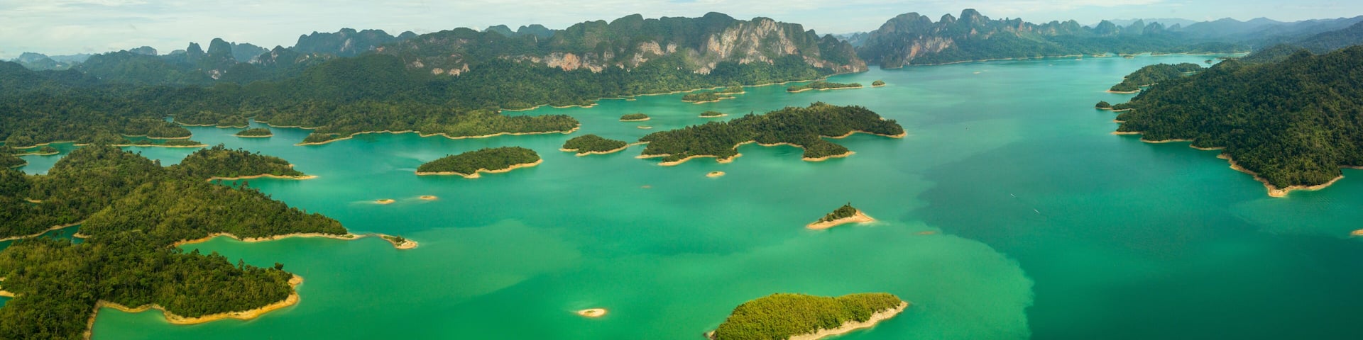 A coastal landscape with numerous small islands surrounded by turquoise waters and dense green forests.
