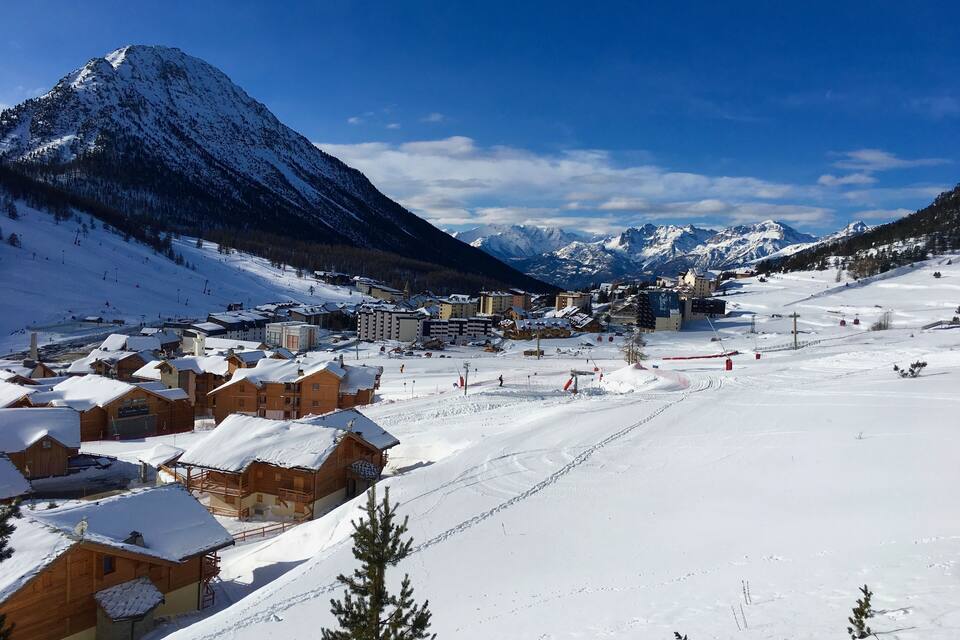 A snow-covered mountain town with wooden buildings and ski slopes.