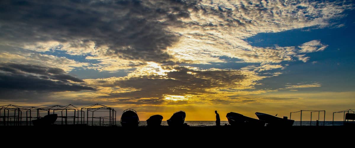 Sunset at the coast of Puerto Lopez, Pacific Ocean, Ecuador with silhouettes of boats (Panorama)