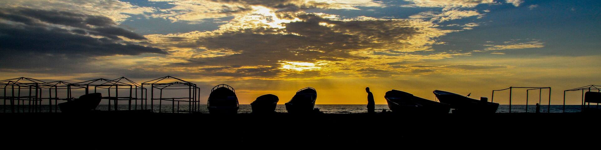 Sunset at the coast of Puerto Lopez, Pacific Ocean, Ecuador with silhouettes of boats (Panorama)