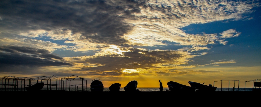 Sunset at the coast of Puerto Lopez, Pacific Ocean, Ecuador with silhouettes of boats (Panorama)