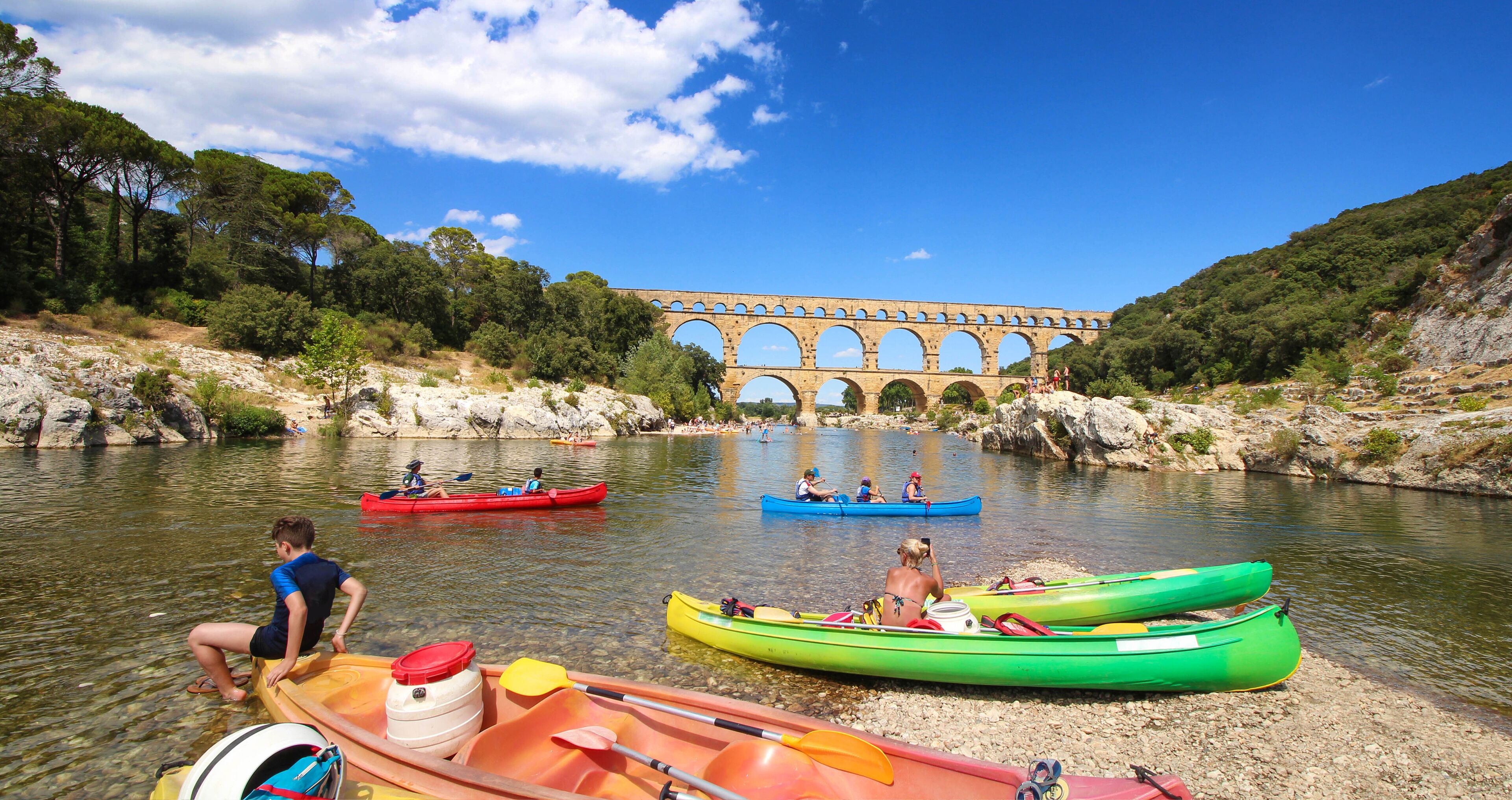 A river with kayaks, a bridge, and a rocky landscape.