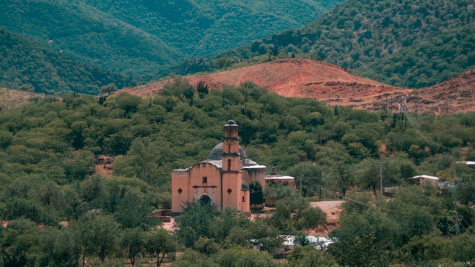 A church surrounded by dense forest and hills.