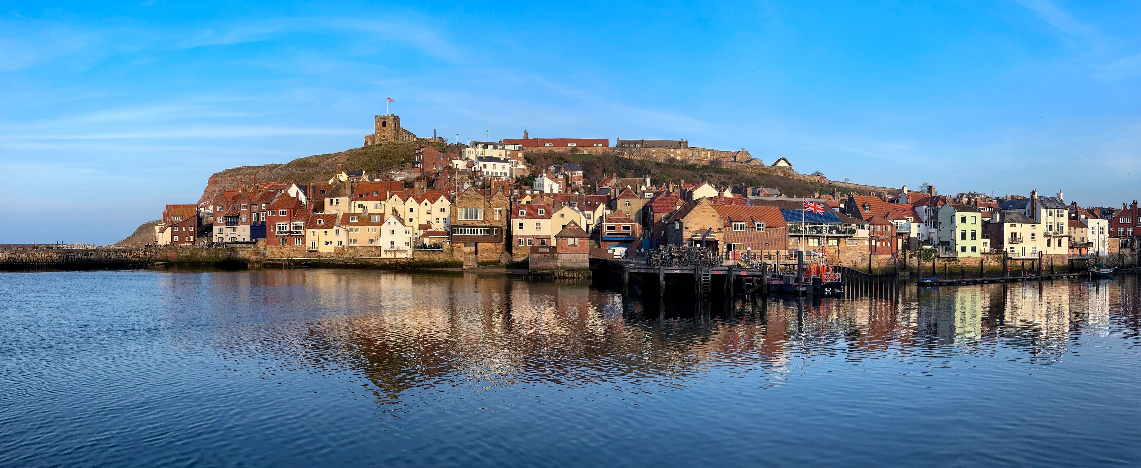 A coastal town with historic buildings and a prominent castle on a hill.