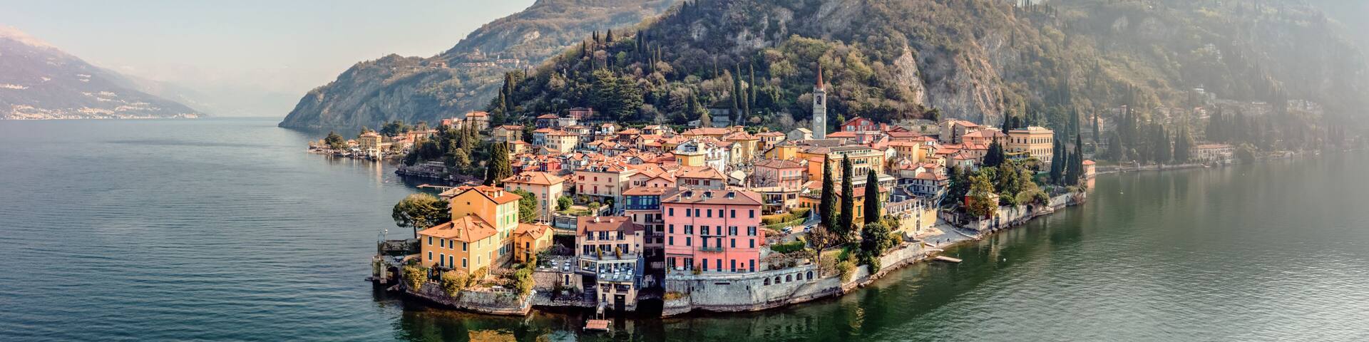 A coastal town with colorful buildings, a river, and mountains in the background.