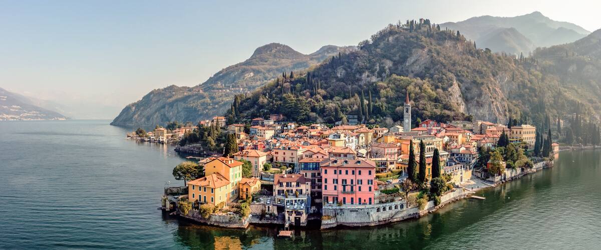 A coastal town with colorful buildings, a river, and mountains in the background.