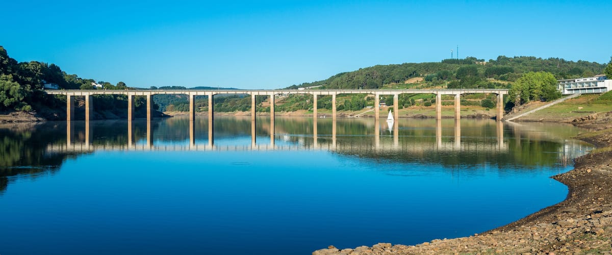 A bridge over a calm river with a clear blue sky.