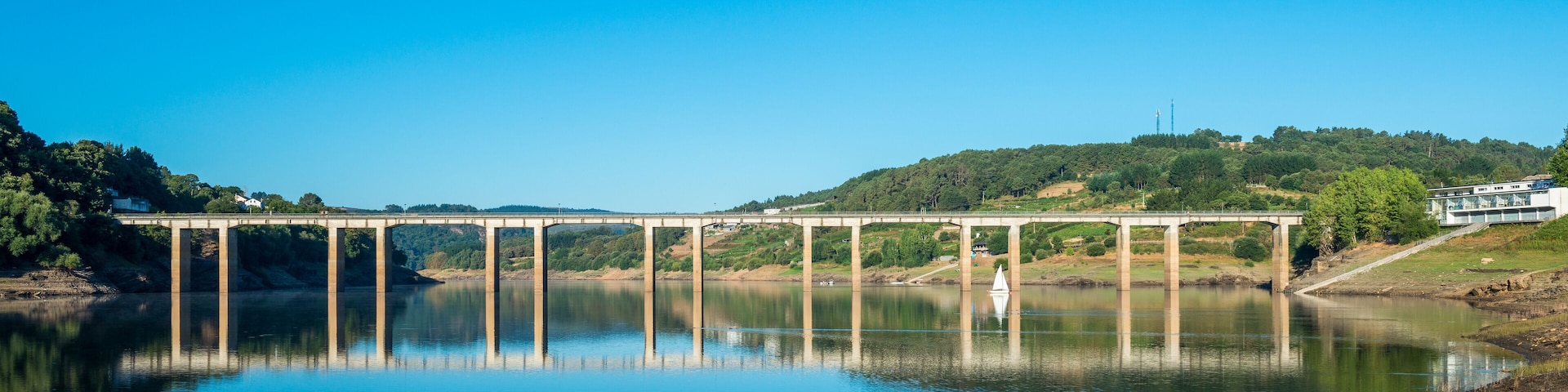 A bridge over a calm river with a clear blue sky.