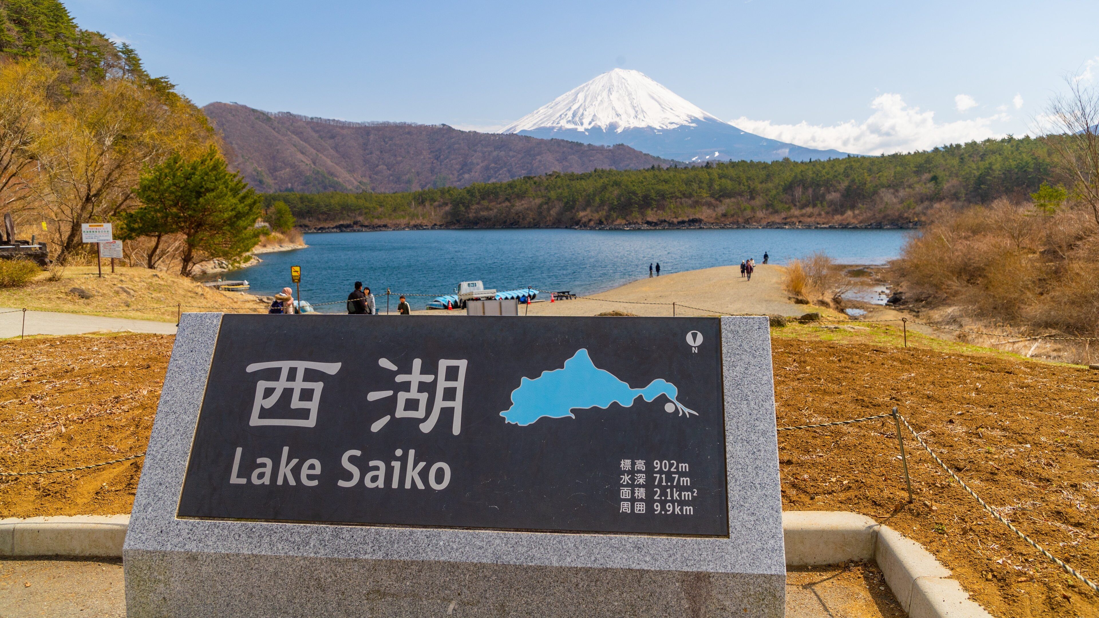 A sign for Lake Saiko with a map, and a view of Mount Fuji in the background.