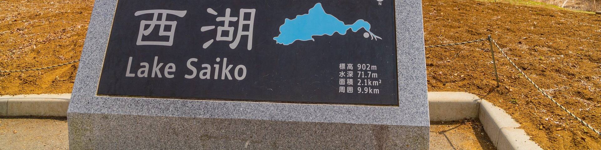 A sign for Lake Saiko with a map, and a view of Mount Fuji in the background.