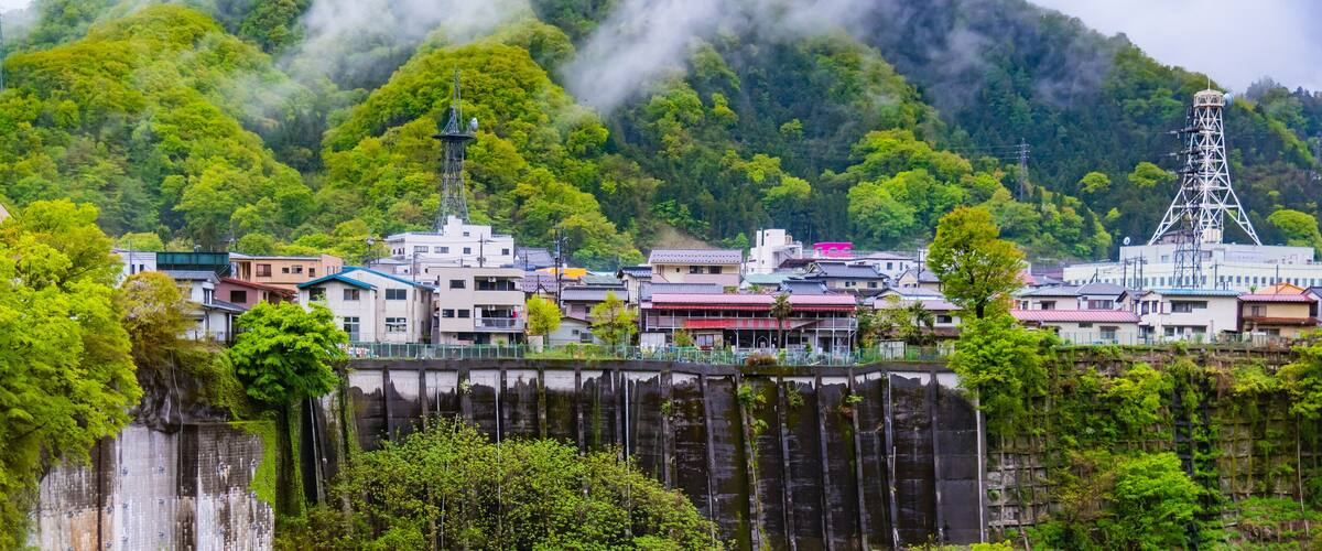A town with buildings and a dam in a mountainous area.
