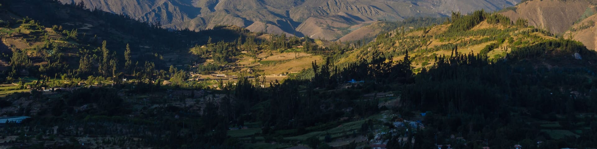 Huascaran mountain in Peru with its two snowy peaks rising over green valley where the town of Yungay sits, destroyed by a flood