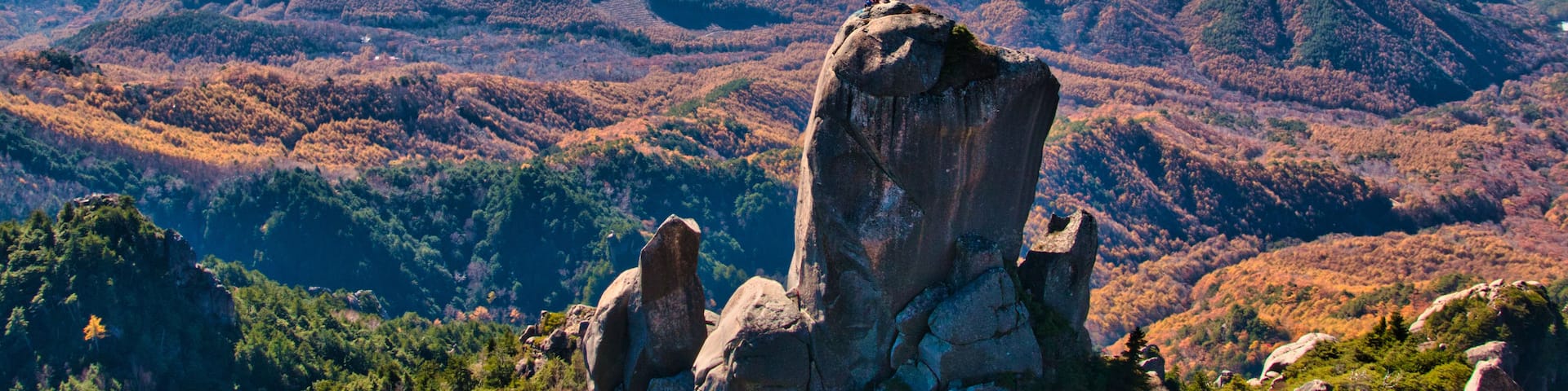 A mountainous landscape with prominent rock formations and a distant mountain range.