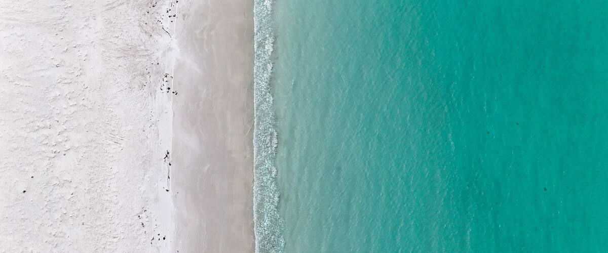 A beach with white sand and turquoise water.