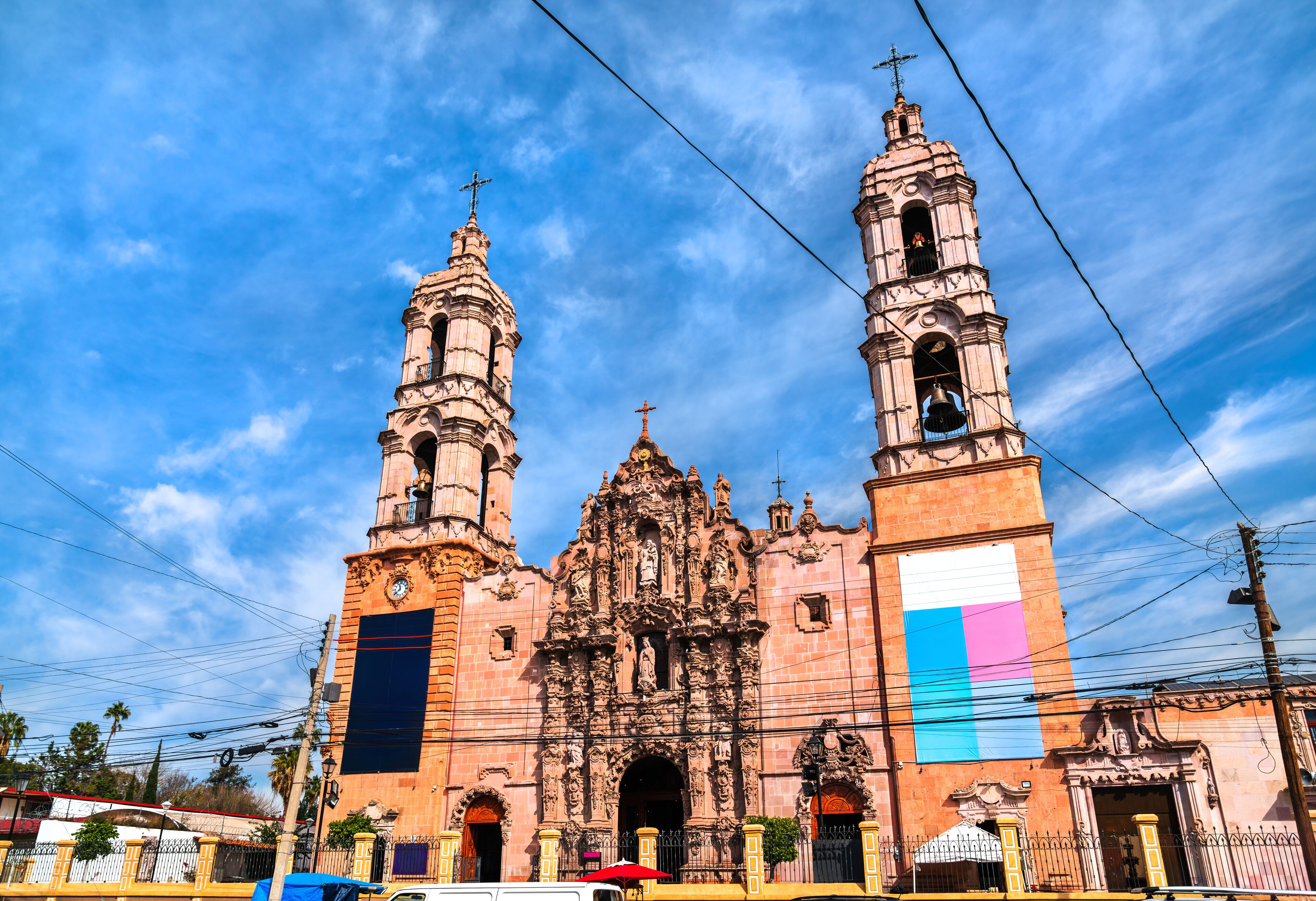 A historic church with two bell towers and a large flag.