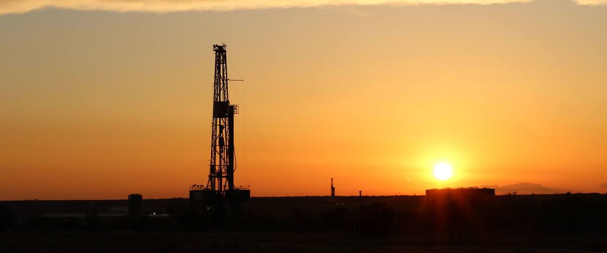 A sunset with a drilling rig silhouetted against the sky.