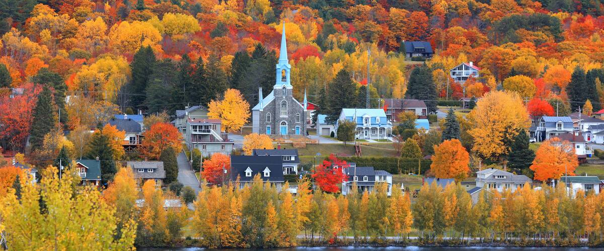 A lakeside town with autumn foliage, a church, and residential houses.