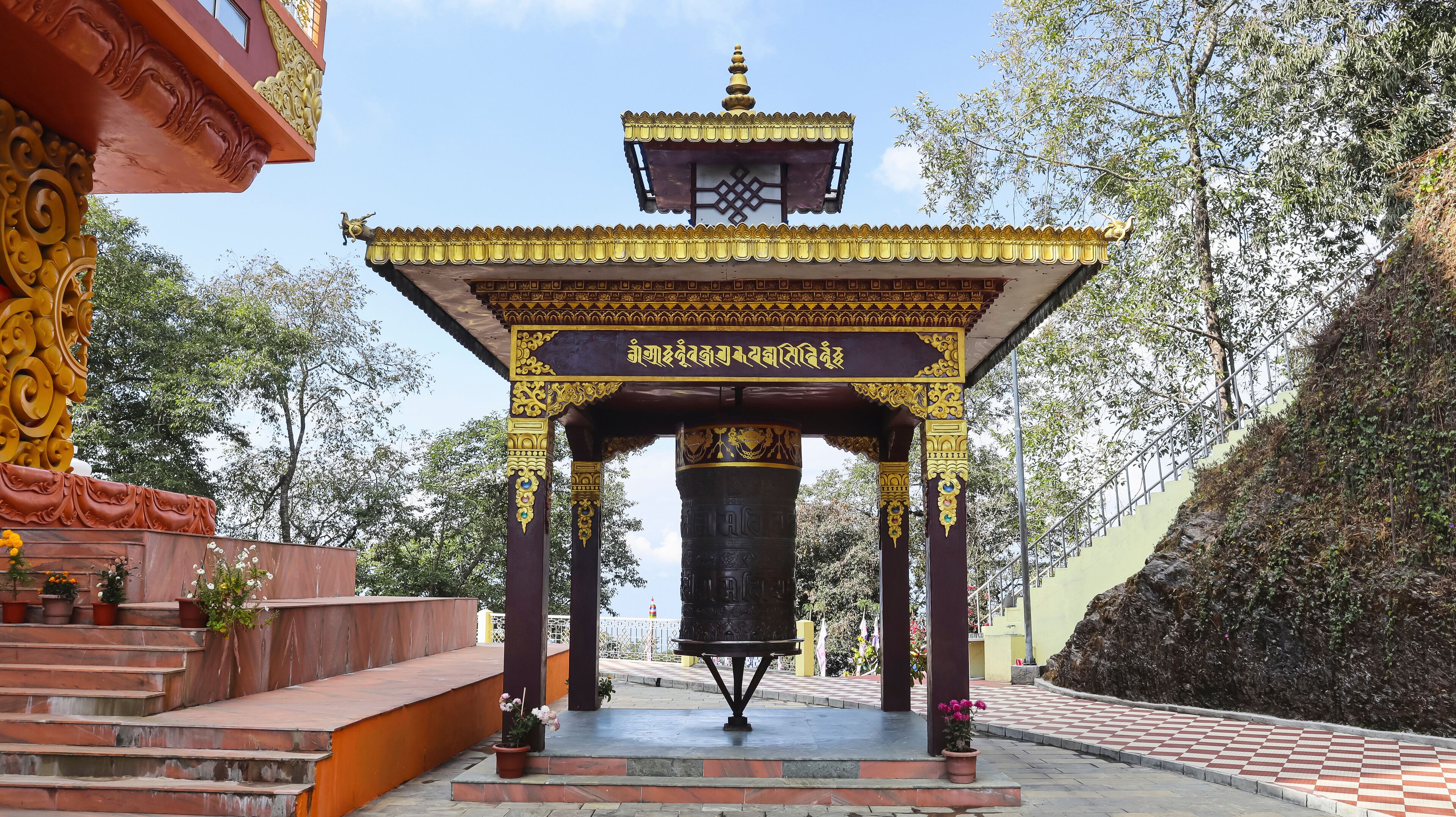 A traditional temple with a bell tower, ornate pillars, and a checkered pathway.