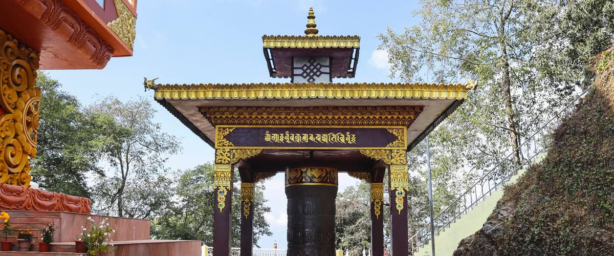 A traditional temple with a bell tower, ornate pillars, and a checkered pathway.