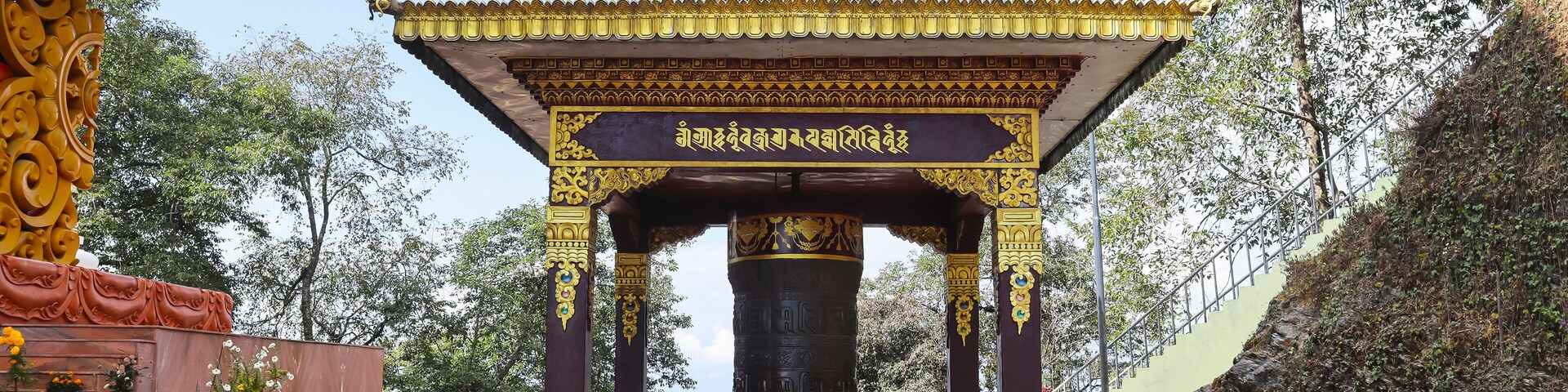 A traditional temple with a bell tower, ornate pillars, and a checkered pathway.