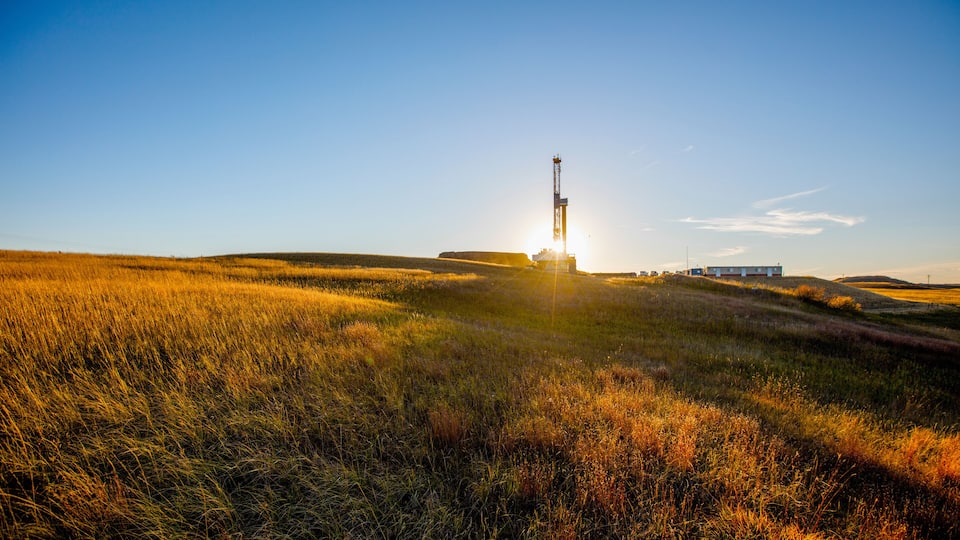 A field with a launch tower and a building in the background.