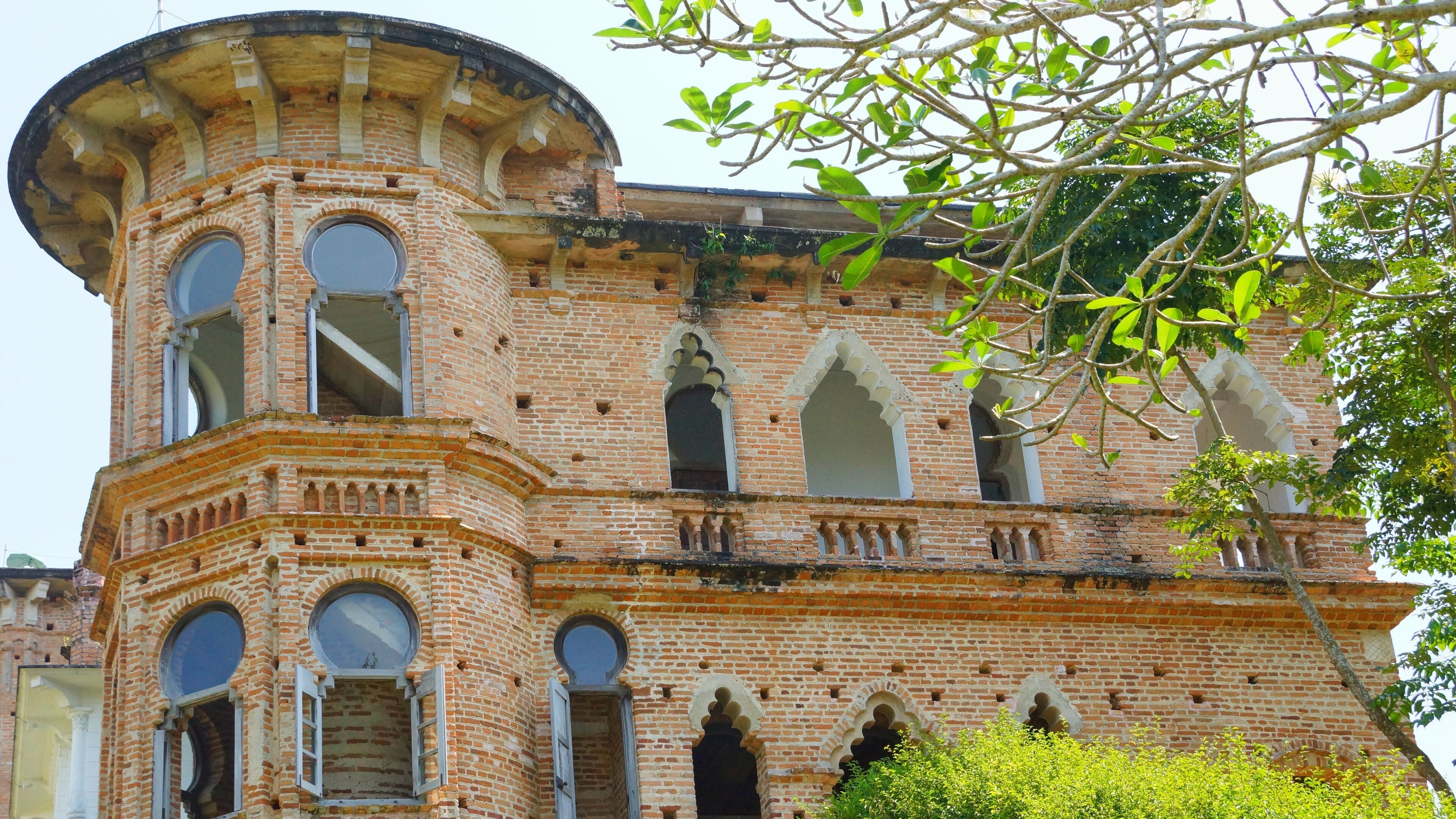 A historic brick building with arched windows and a turret.