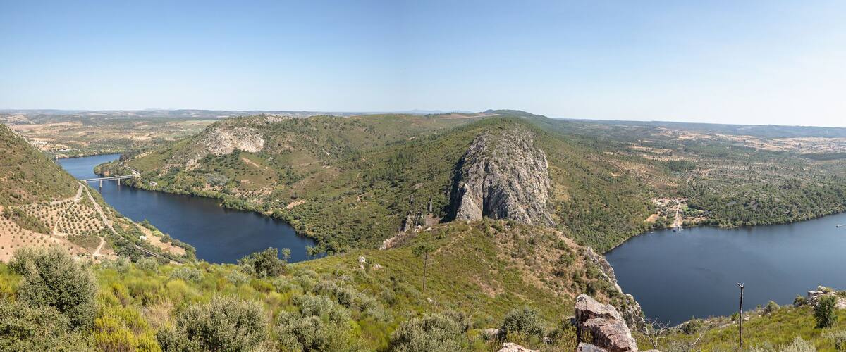 A river winding through a mountainous landscape with dense forests and rocky cliffs.