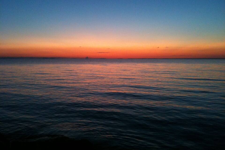 A calm sea at sunset with a clear horizon.