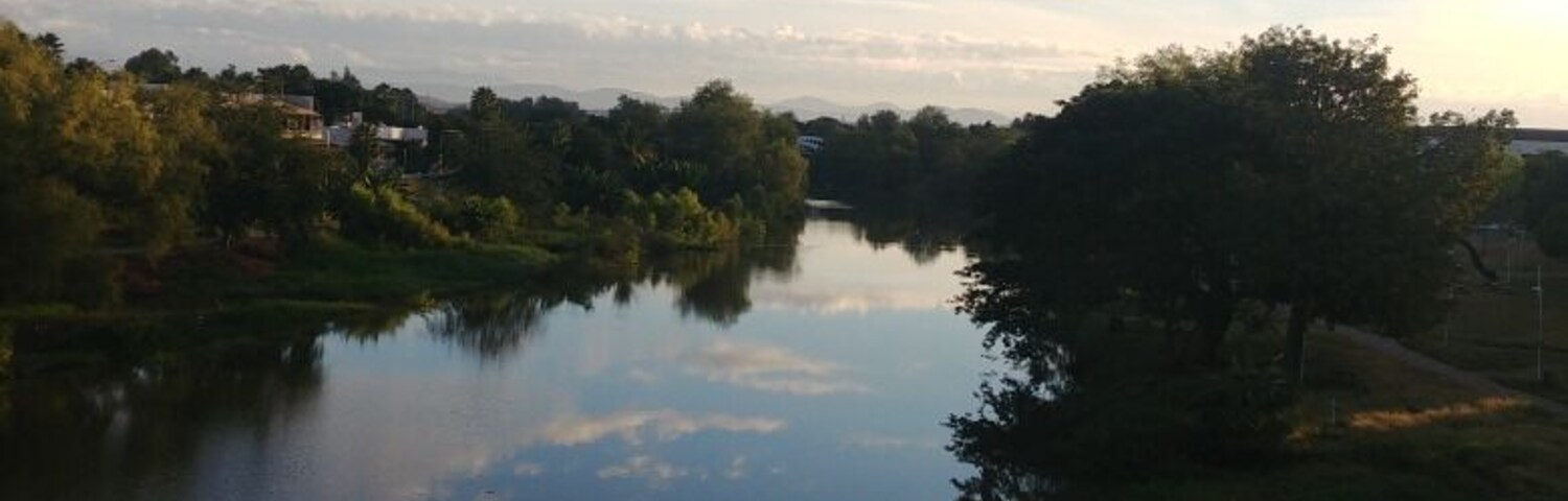 Un río tranquilo que refleja el cielo y los árboles.