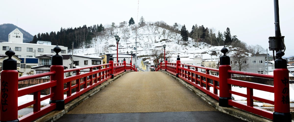 A red bridge with a snow-covered mountain in the background.