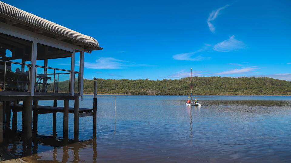 A lakeside pier with a boat in the distance.