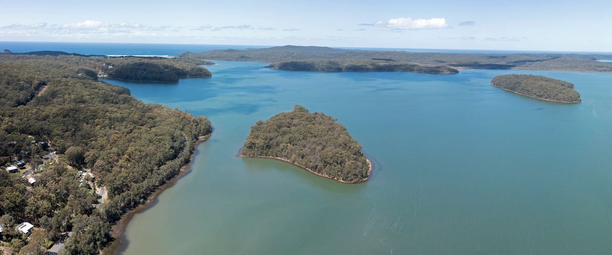 A coastal landscape with a large body of water surrounded by forested hills.