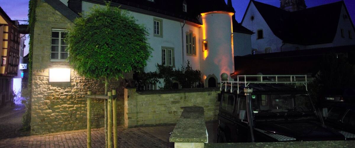 A historic building with a tower, a stone wall, and a bench.