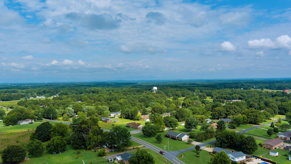 A rural landscape with a prominent white dome structure, surrounded by lush greenery and residential areas.
