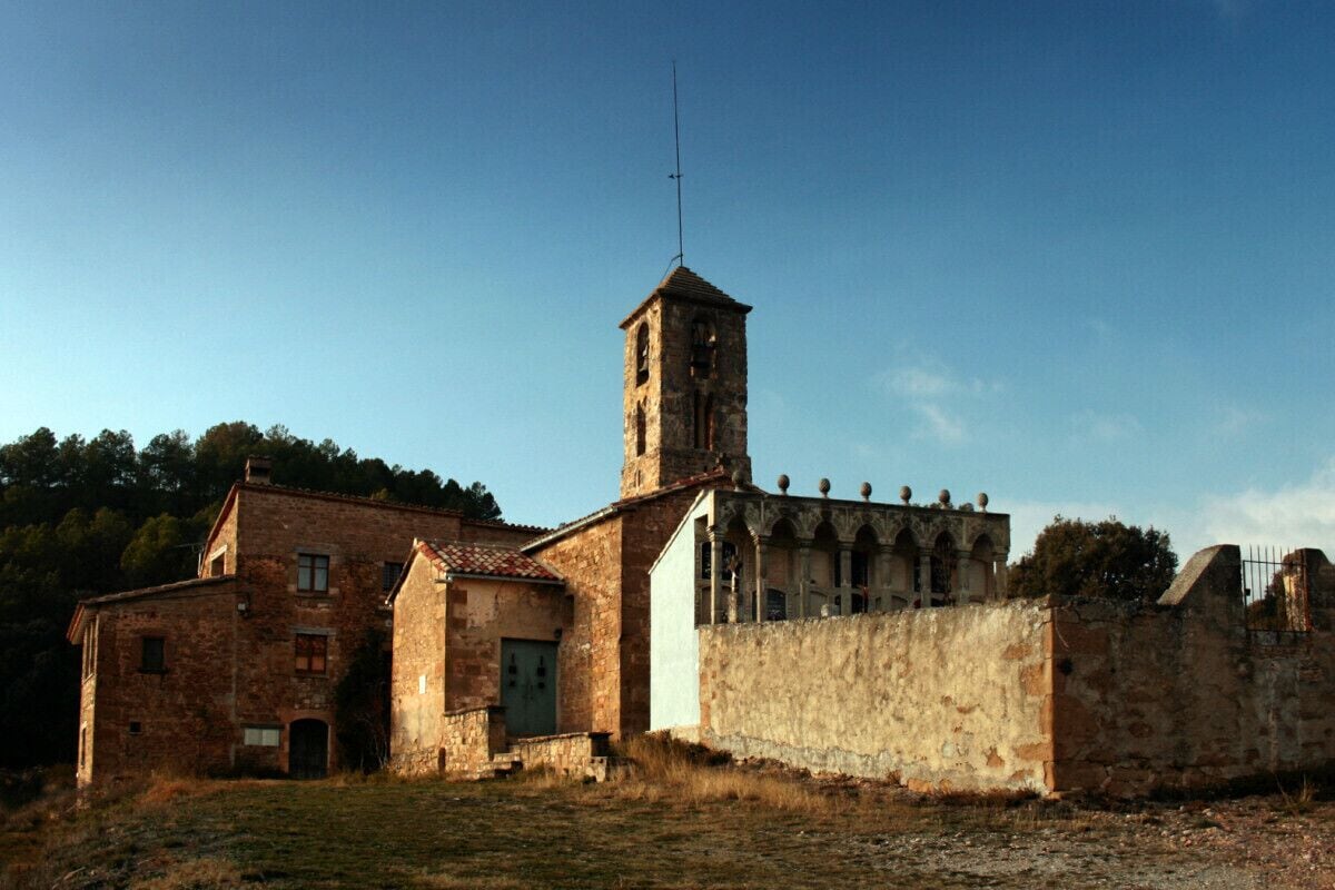 A stone church with a bell tower and a small bell.
