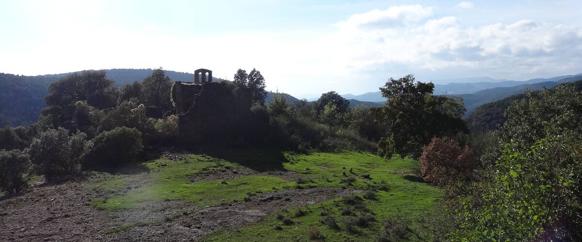A lush green valley with a historic stone structure on a hill.