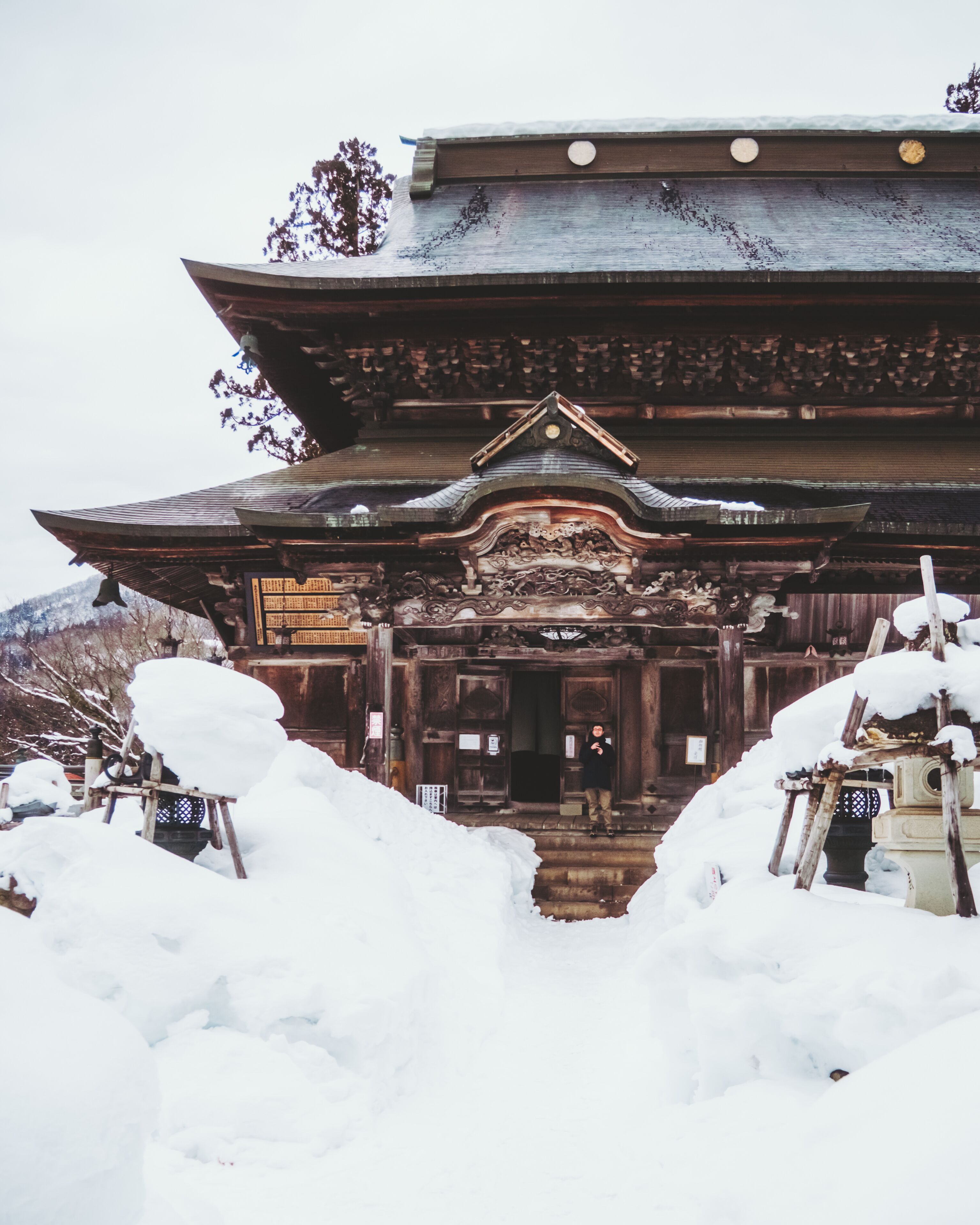 View of the snow-laden Enzoji Temple, its dark wood contrasting with the pristine white, a serene scene frozen in time, Yanaizu, Fukushima, Japan.