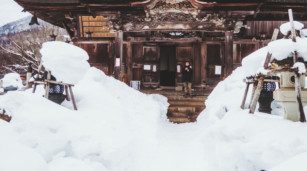 View of the snow-laden Enzoji Temple, its dark wood contrasting with the pristine white, a serene scene frozen in time, Yanaizu, Fukushima, Japan.