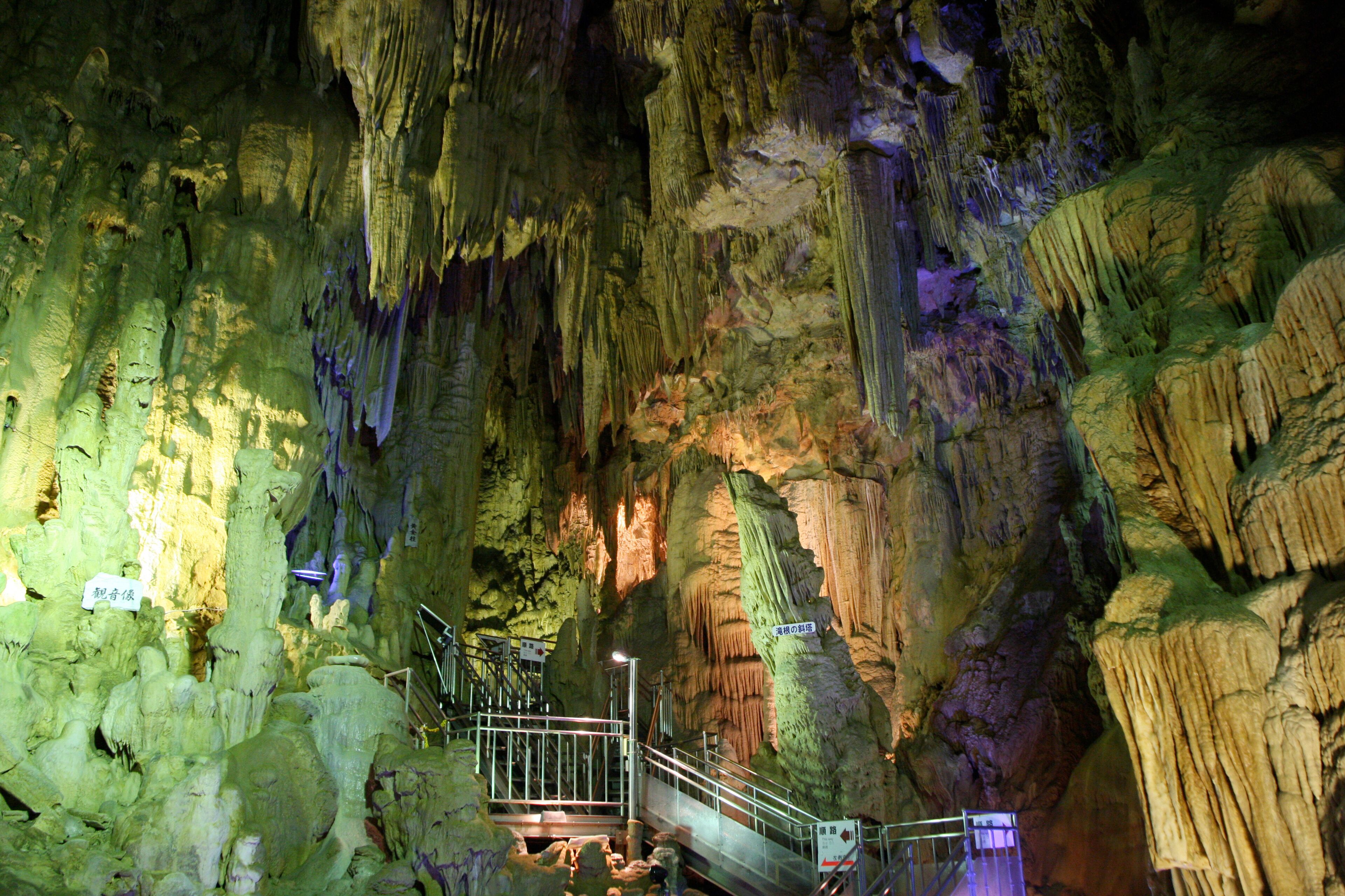 A cave with stalactites and stalagmites, a walkway, and a sign in Chinese.