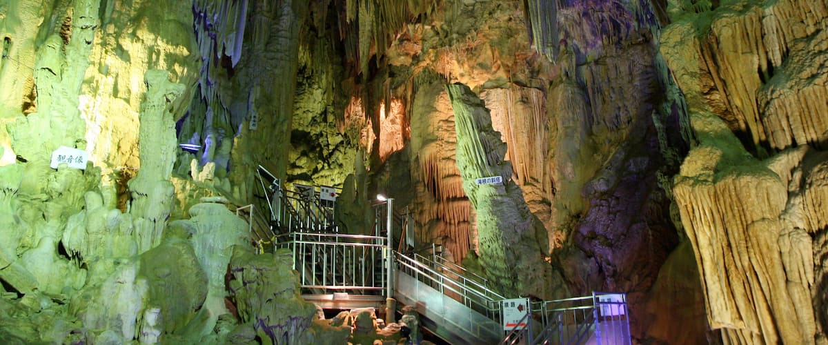A cave with stalactites and stalagmites, a walkway, and a sign in Chinese.